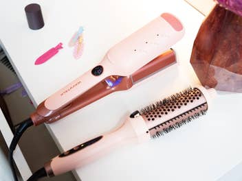 Zwei Produkte fürs Haarstyling der Firma Wavytalk liegen auf einem Tisch nebst Deko und Haarspangen