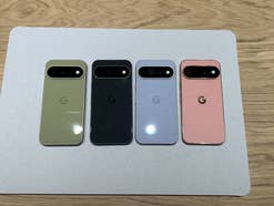 Vier Google Pixel Smartphones in Grün, Schwarz, Hellblau und Rosa nebeneinander auf einer hellgrauen Unterlage.