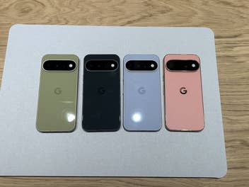 Vier Google Pixel Smartphones in Grün, Schwarz, Hellblau und Rosa nebeneinander auf einer hellgrauen Unterlage.