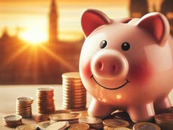 Sparschwein steht neben Geldmünzen im Sonnenlicht.