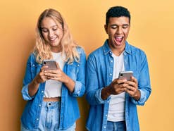 Mädchen und Junge nutzen mit Spaß ein Smartphone