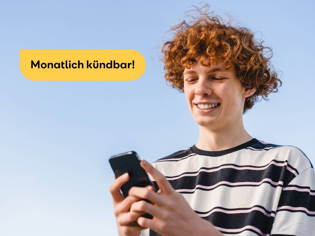 Junger Mann lächelt in sein Smartphone