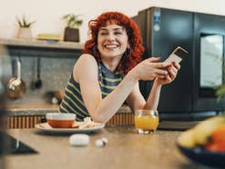 Eine Person hält ein Smartphone in der Hand und freut sich über die neuen Gesetze der EU, die auch ihr Smartphone in Zukunft besser machen