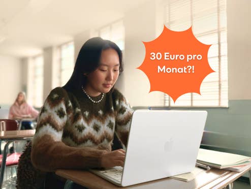 Eine Frau sitzt an einem Schreibtisch mit dem Apple MacBook Neo