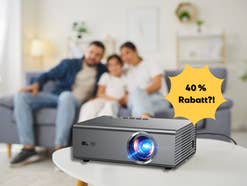 Eine Familie sitzt im Wohnzimmer hinter einem Beamer