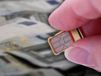 5-Euro-Scheine im Hintergrund davor eine Hand die eine SIM-Karte hält