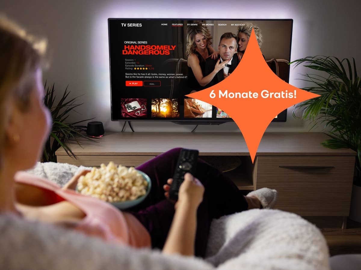 Frau sitzt auf dem Sofa mit Popcorn und guckt Fernseh.