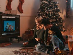 Eine Frau und ein Mann puzzeln in einem Weihnachtszimmer, während ein Weihnachtsfilm läuft.