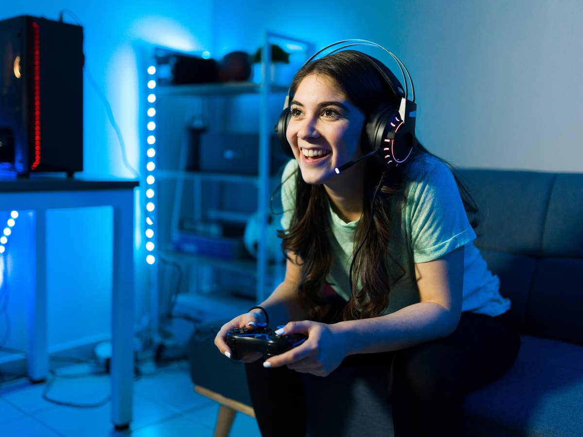 Junge Frau sitzt vor einem Ferneher und spielt ein Computerspiel.
