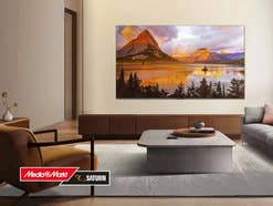 Ein QLED-TV hängt an einer Wand, davor ist ein MediaMarkt-Logo zu sehen.