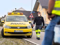 Ein ADAC-Mitarbeiter geht neben dem gelben ADAC-Auto zu einem Panneneinsatz.