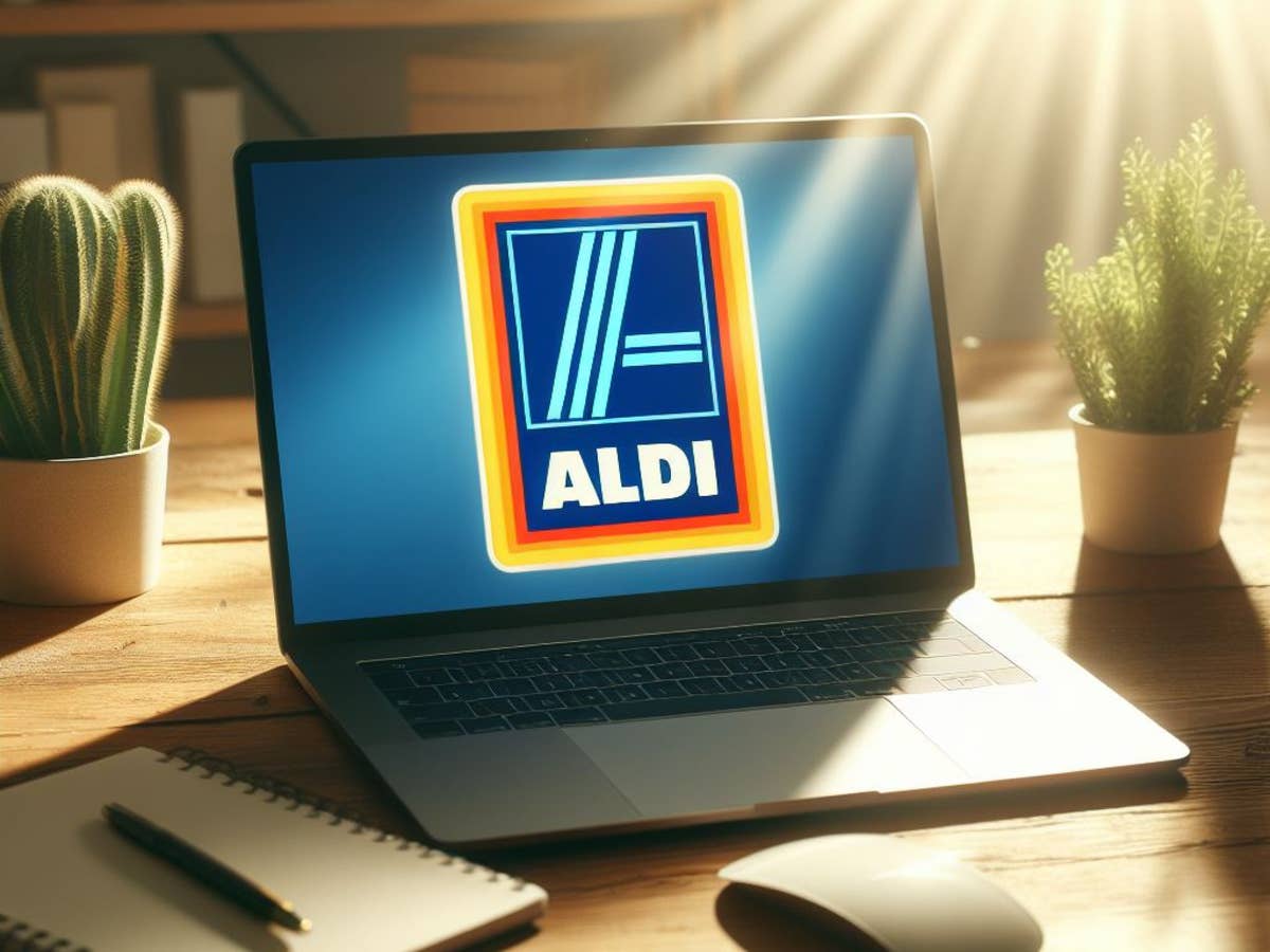 Notebook mit Aldi-Logo auf dem Display steht im Sonnenlicht auf einem Schreibtisch.