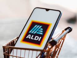 Smartphone mit Aldi-Logo im Display liegt in einem Mini-Einkaufswagen.