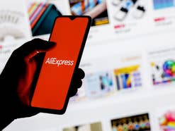 Eine Hand hält ein Smartphone mit dem AliExpress Logo darauf