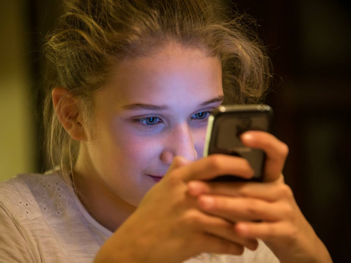 Mädchen starrt gebannt auf den Bildschirm von ihrem Smartphone.