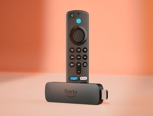 Amazon Fire TV Stick mit Fernbedienung vor kupferfarbenem Hintergrund.