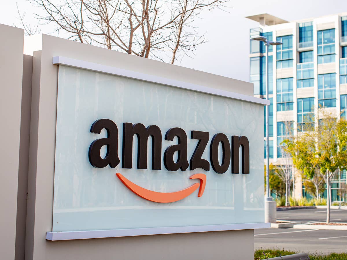 Amazon: Käufer erhalten Ware und werden angezeigt Amazon-Logo vor Gebäude