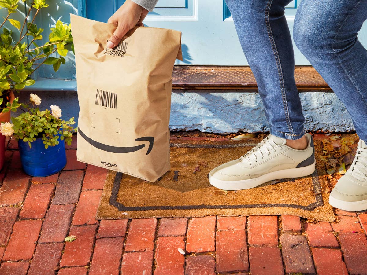 Ein Kunde hebt eine Amazon-Lieferung auf, die vor seiner Tür steht