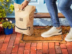 Ein Kunde hebt eine Amazon-Lieferung auf, die vor seiner Tür steht