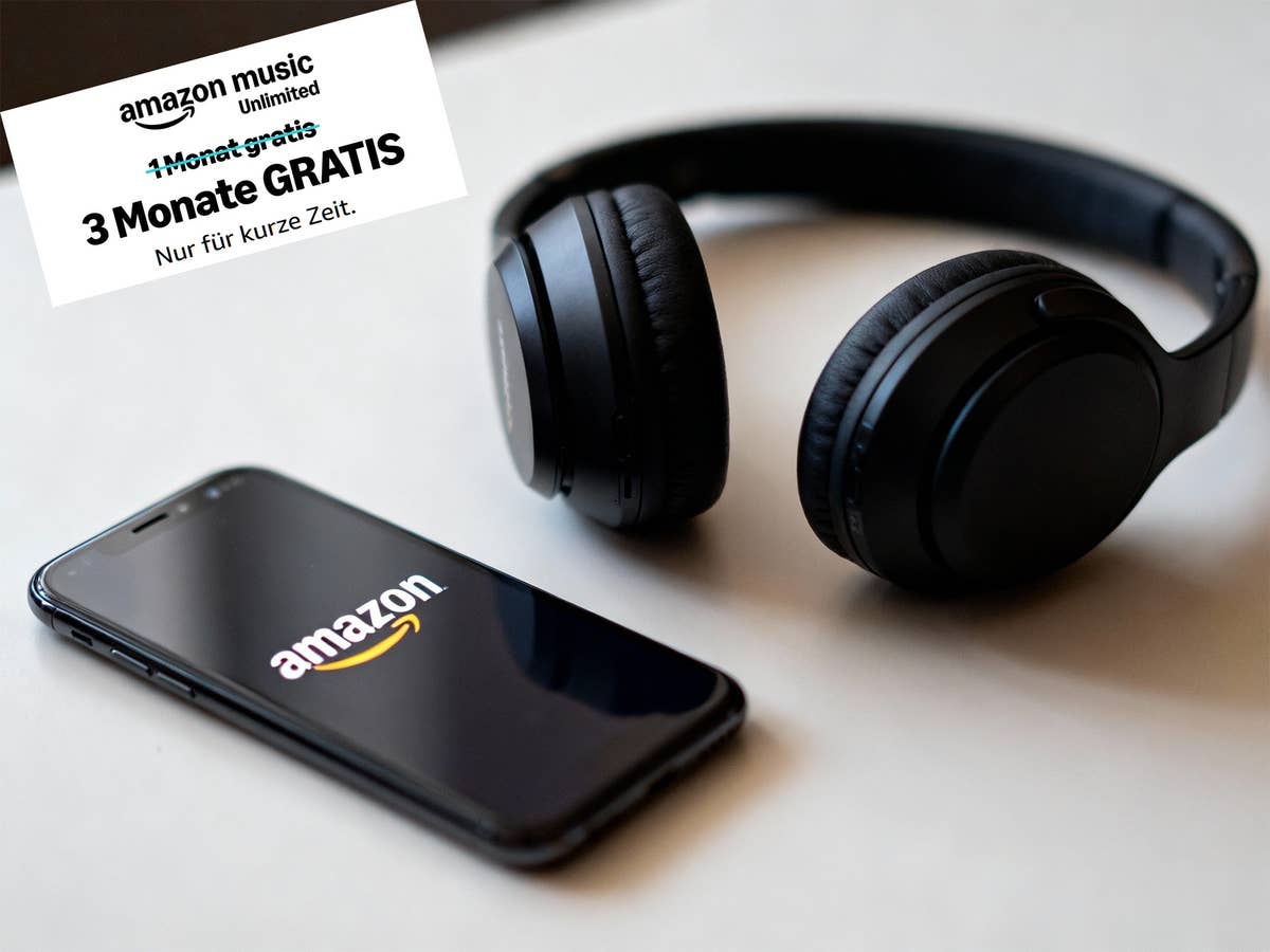 Amazon-Logo auf eienm Smartphone. Daneben ein schwarzer Kopfhörer auf einem weißen Tisch. In der linken oberen Ecke ist zu erkennen, dass es Amauon Music Unlimited 3 Monate gratis gibt.