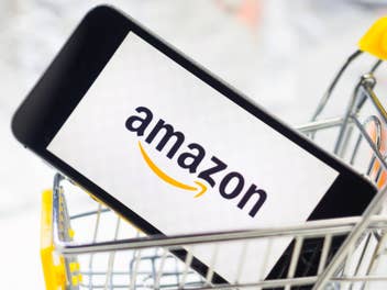 Amazon Logo auf einem Smartphone in einem Einkaufswagen.