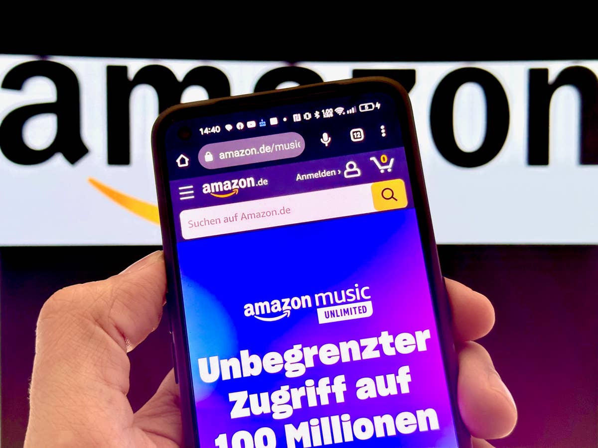 Amazon Music auf einem Smartphone vor Amazon-Logo im Hintergrund.