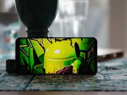Handy mit Foto einer Android-Figur auf dem Bildschirm steht auf dem Tisch
