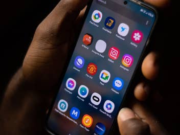 Android-Smartphone mit Apps in der Hand eines Mannes vor dunklem Hintergrund.