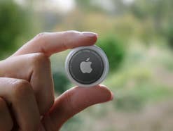 Apples AirTag zwischen zwei Fingern