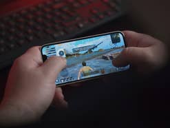 Eine Person hält ein iPhone, auf dem das Spiel PUBG Mobile läuft