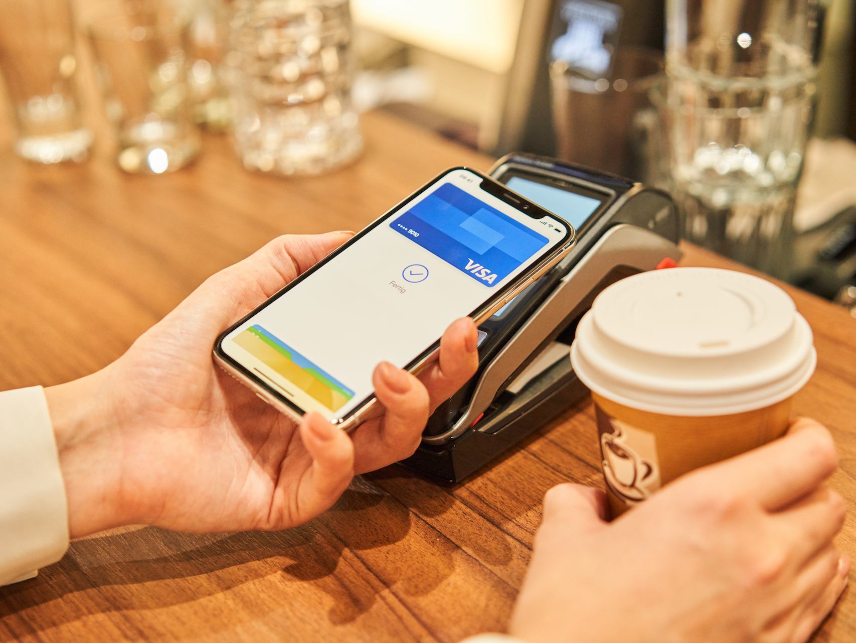 Ein iPhone X wird im Café zum Bezahlen an ein Kartenlesegeröt gehalten