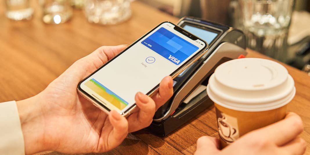 Ein iPhone X wird im Café zum Bezahlen an ein Kartenlesegeröt gehalten