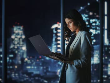 Eine Frau arbeitet im Stehen mit einem Laptop von Asus.