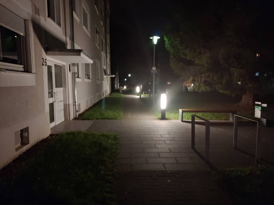 Wohnblock bei Nacht, Lampen illuminieren den Gehweg