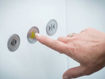 Ein Finger drückt auf den Notrufknopf im Aufzug