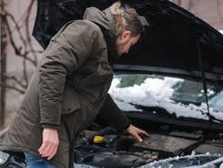 Mann steht vor Auto im Winter