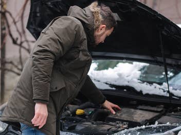 Mann steht vor Auto im Winter