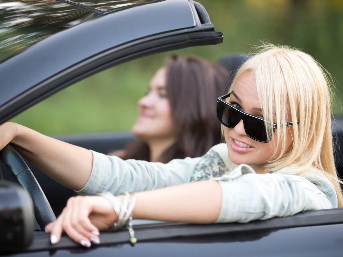 Blonde Frau in einem Auto hinter dem Steuer.