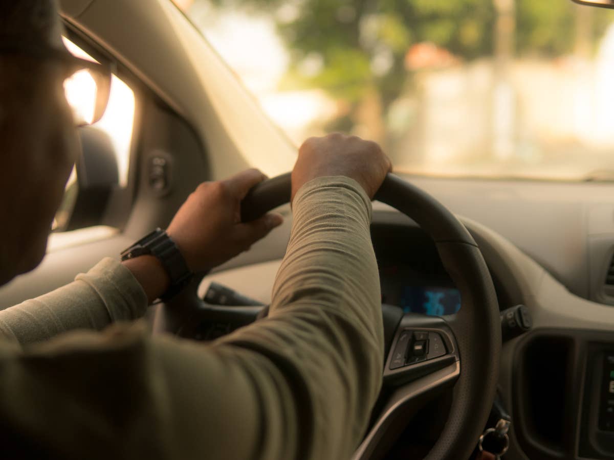 Ein Mann sitzt in einem Auto am Lenkrad und fährt