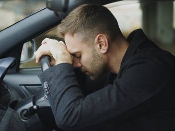 Autofahrer lehnt frustriert am Lenker
