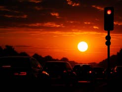 Autos an einer Ampel vor einem Sonnenuntergang.