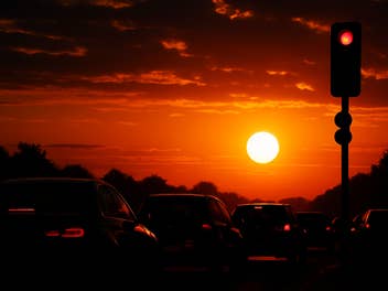 Autos an einer Ampel vor einem Sonnenuntergang.