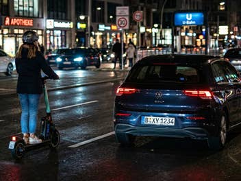 Autos und E-Scooter fahren nachts auf einer Straße