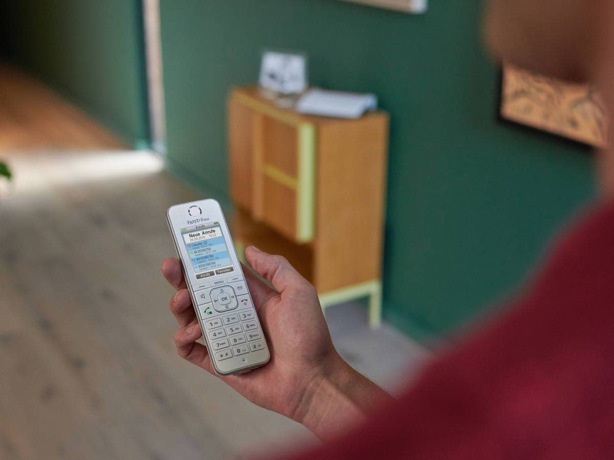 Festnetz-Telefon von AVM in der Hand eines Mannes.