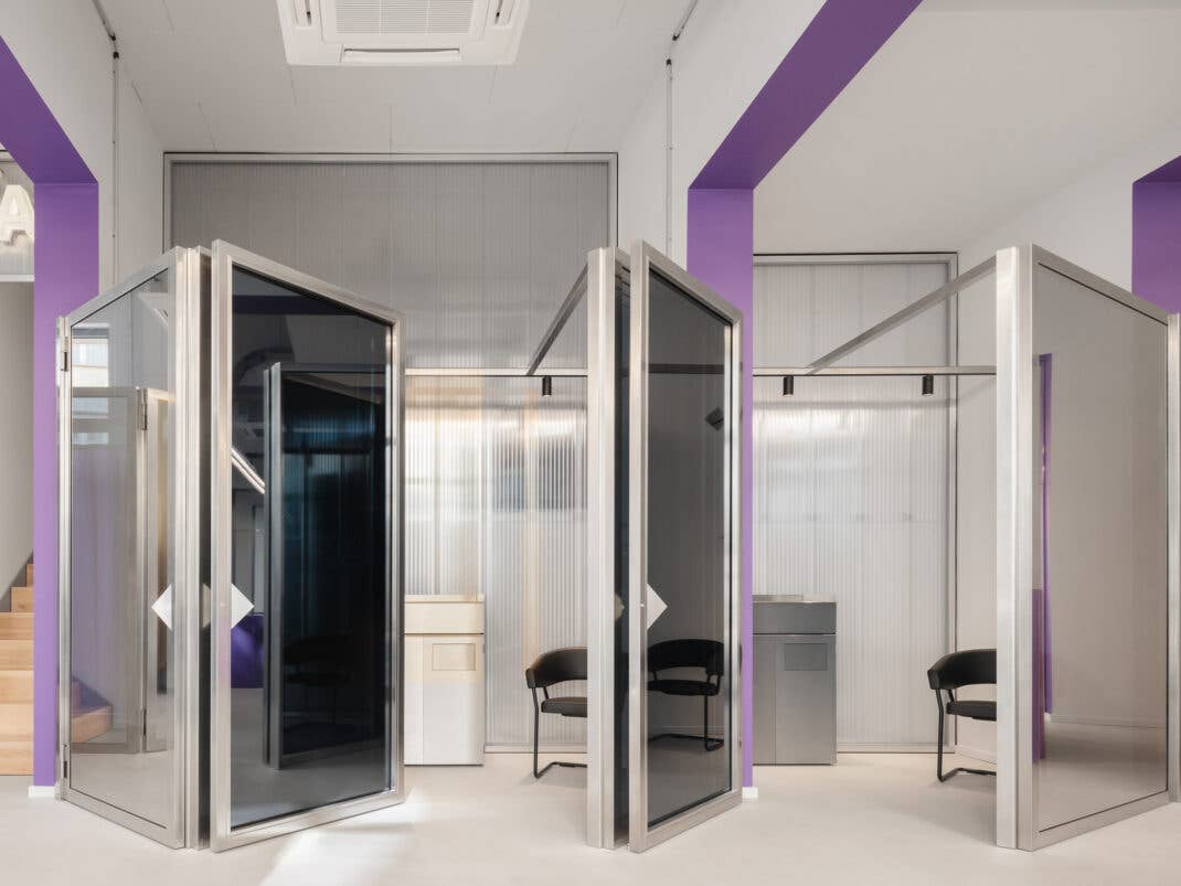 Moderne Büros mit transparenten Kabinen und einer Treppe, mit lila Akzenten.
