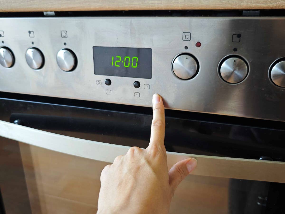 So stellst du die Uhrzeit an deinem Backofen ein. eine Hand zeigt auf die Tasten eines Backofens