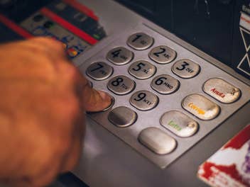 Eine Hand tippt auf den Tasten eines Geldautomats