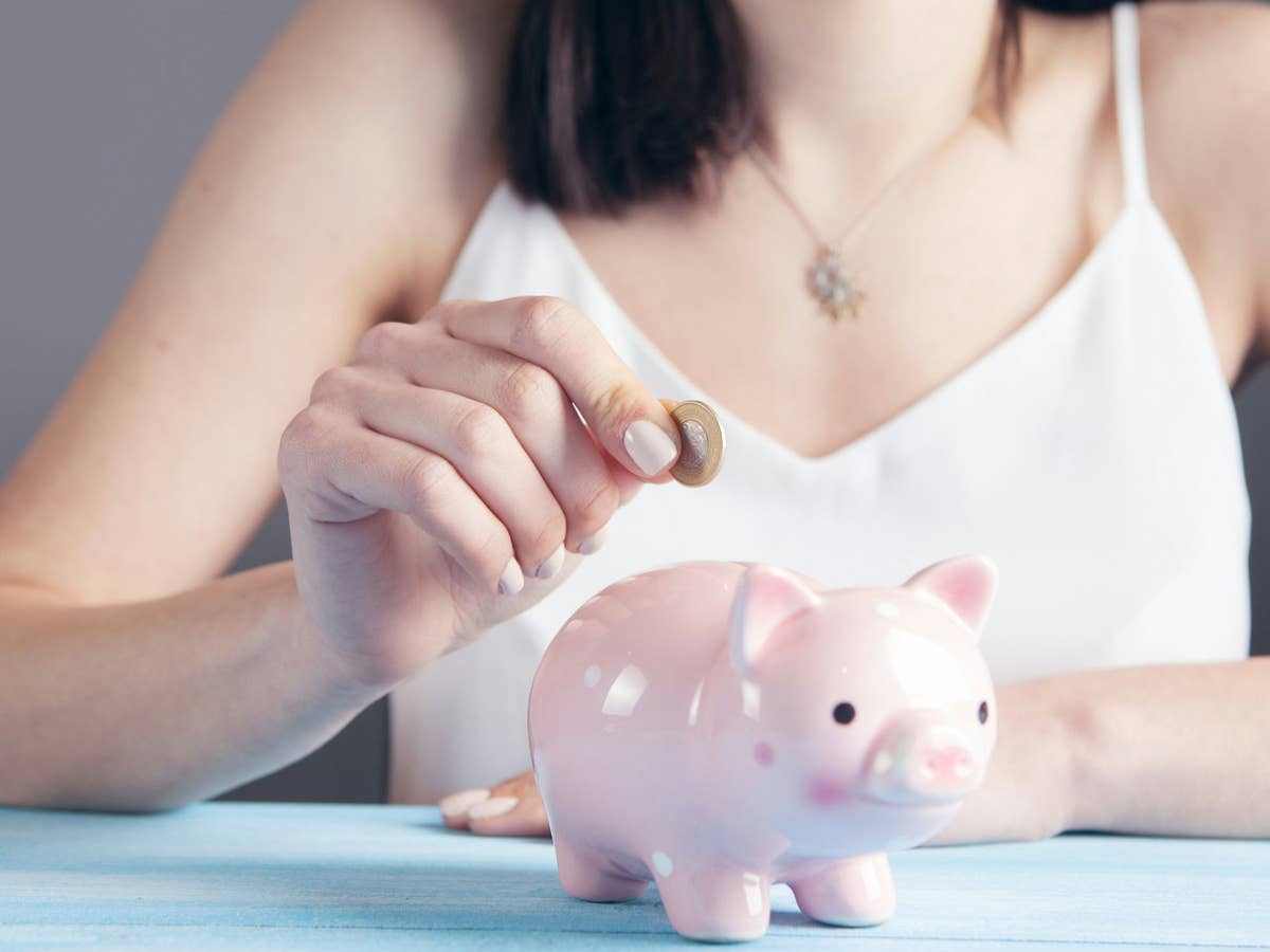 Tagesgeld vs. Festgeld: Bei dieser Bank gibt's drei Jahre lang 3,2 Prozent Zinsen Frau steckt eine Münze in ein Sparschwein