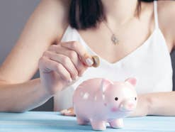 Frau steckt eine Münze in ein Sparschwein