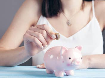 Frau steckt eine Münze in ein Sparschwein